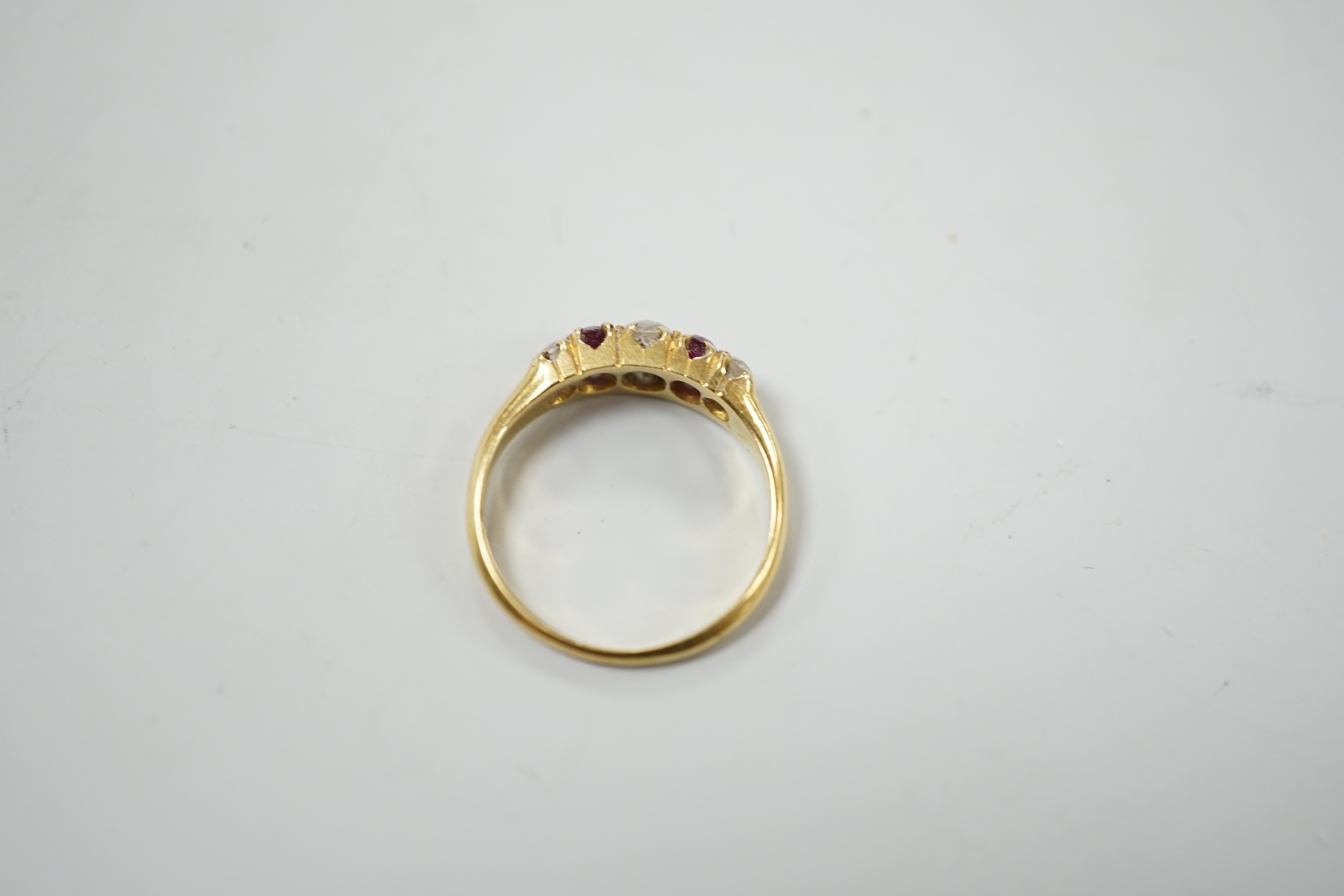 A yellow metal, two stone ruby and three stone diamond set half hoop ring, size J, gross weight 2.2 grams.